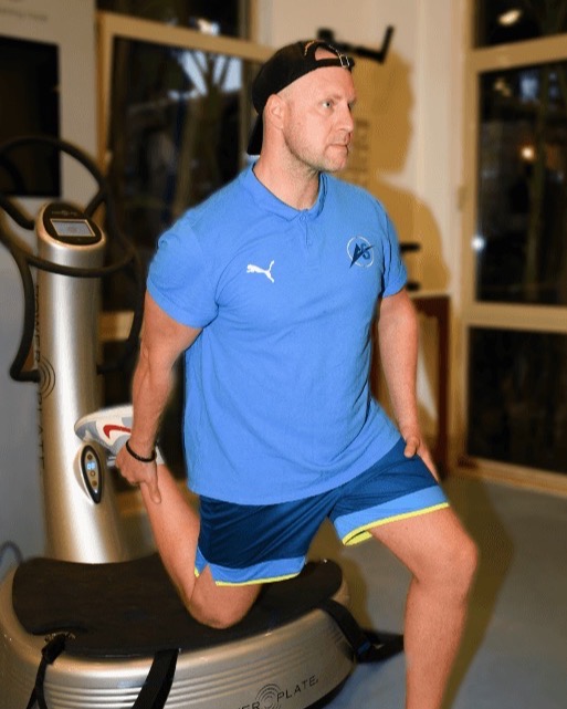 Steffen Albert, Gründer von AS Physio, mit einem Bein auf der Power Plate im Trainingsraum