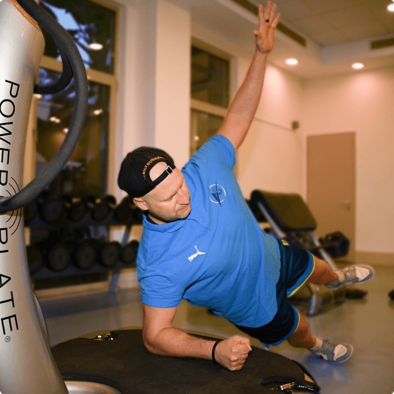Seitstütz mit ausgestrecktem Arm auf einer Power Plate im Trainingsraum